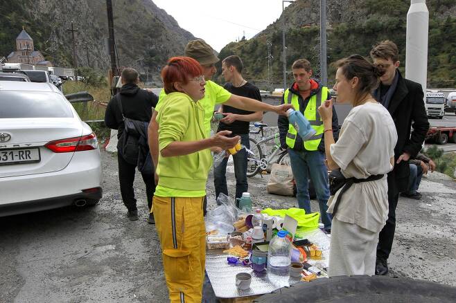 28일 조지아 국경을 넘은 러시아 사람들이 휴식 시간에 식사를 하고 있다. AP=연합뉴스