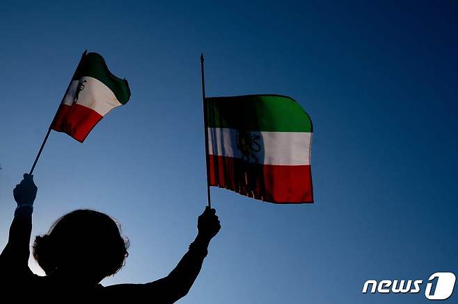 15일(현지시간) 미국 워싱턴DC에서 열린 이란 반정부 시위에 참여한 한 여성이 양손에 이란 국기를 들고 있다. 2022.10.15 ⓒ AFP=뉴스1 ⓒ News1 정윤미 기자