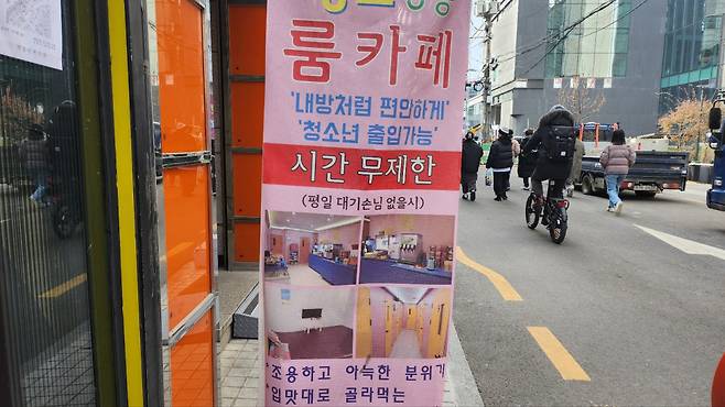 Pedestrians walk by a banner advertising a room cafe in Mapo-gu, Seoul, which mentions "Adolescents are allowed." (Lee Jung-youn/The Korea Herald)