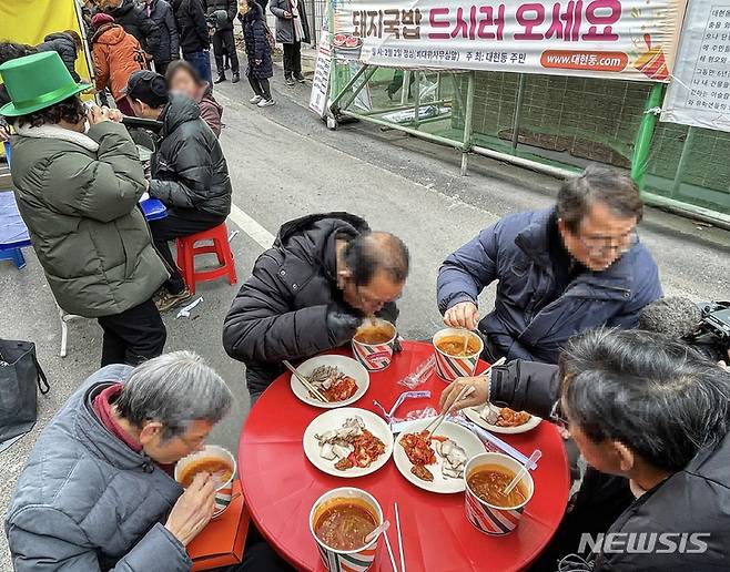 [대구=뉴시스] 정재익 기자 = 2일 오후 대구 북구 이슬람사원 공사현장 앞에서 대현동 주민들이 돼지수육과 소고기국밥을 먹고 있다. 2023.02.02. jjikk@newsis.com