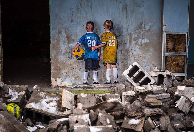 2월 1일 우크라이나 이르핀의 문화센터 건물벽에 그려진 이탈리아 거리 예술가 TvBoy의 그림. 그림 속 두 소년의 축구 유니폼에 각각 '평화'와 '희망'이라고 쓰여 있다./AFP 연합뉴스