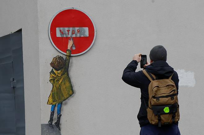 1월 29일 우크라이나 부차의 마을회관에 이탈리아 거리 예술가 TvBoy가 그린 소녀의 그림. 그림속 소녀가 전쟁(WAR)이라고 씌여진 벽에 '멈춰(STOP)'라고 쓴 팻말을 들고 있다. /로이터 뉴스1