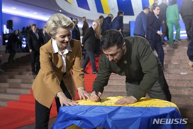 [키이우=AP/뉴시스] 볼로디미르 젤렌스키(오른쪽) 우크라이나 대통령이 2일(현지시간) 키이우에서 열린 유럽연합(EU)-우크라이나 정상 회담에서 기념 촬영 전 우르줄라 폰데어라이엔 EU 집행위원장과 함께 우크라이나 국기에 서명하고 있다. 2023.02.03.