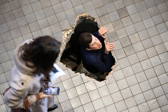 뜬금없이 미술관 바닥을 뚫고 머리를 내민 남자는 카텔란의 설치작품 '무제'(2001)이다. [사진 뉴시스]