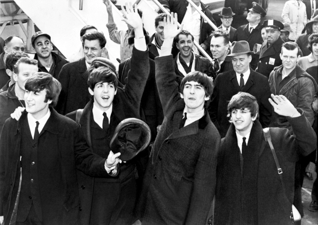 1964년 2월 7일, 미국 뉴욕의 존 F 케네디 국제공항에 도착한 영국의 록밴드 ‘비틀스’가 팬들을 향해 손을 흔들고 있다. 왼쪽부터 존 레넌, 폴 매카트니, 조지 해리슨, 링고 스타.   자료사진