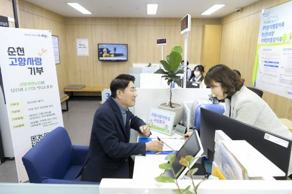 노관규 시장이 NH농협 순천시청출장소를 방문해 고향사랑기부금 신청서를 작성하고 있다.  오른쪽은 송은아 팀장.