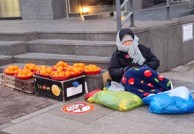 영하 12도까지 떨어졌던 지난달 28일 서울 강남구 지하철 3호선 신사역 부근에서 노점상을 하는 한 할머니가 추운 날씨 속에 귤을 팔고 있다.     필자 제공