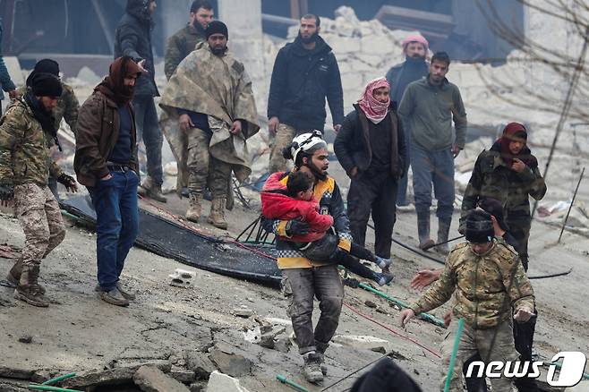 6일(현지시간) 시리아 잔다리스 마을에서 한 구조대원이 지진 현장에서 구조한 어린 아이를 안고 잔해 속을 빠져나오고 있다. ⓒ 로이터=뉴스1 ⓒ News1 권진영 기자