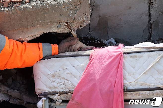 튀르키예 남동부 카라만마라슈의 건물 잔해에서 메수트 한제르라는 남성이 침대 위에서 죽은 딸의 손을 잡고 있다. ⓒ AFP=뉴스1