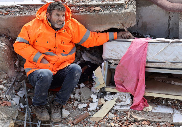 규모 7.8의 강진이 휩쓸고 하루가 지난 7일 튀르키예 남동부 카라만마라슈에서 한 아버지가 무너진 건물 더미에 깔려 숨진 15세 딸의 손을 잡고 앉아 있다. AFP 연합뉴스