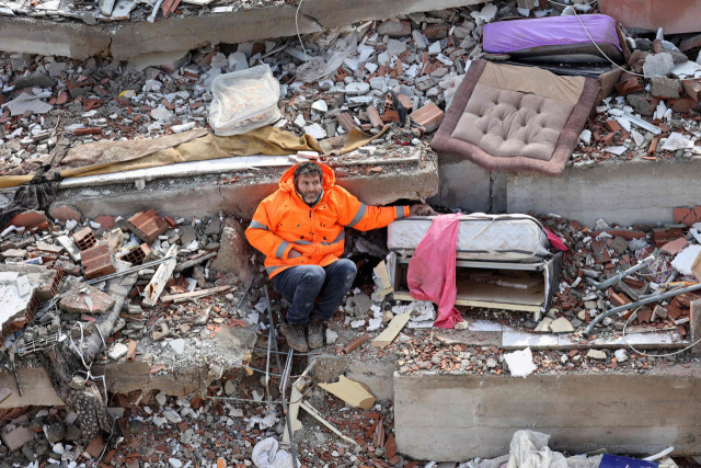 규모 7.8의 강진이 휩쓸고 하루가 지난 7일 튀르키예 남동부 카라만마라슈에서 한 아버지가 무너진 건물 더미에 깔려 숨진 15세 딸의 손을 잡고 앉아 있다. AFP 연합뉴스