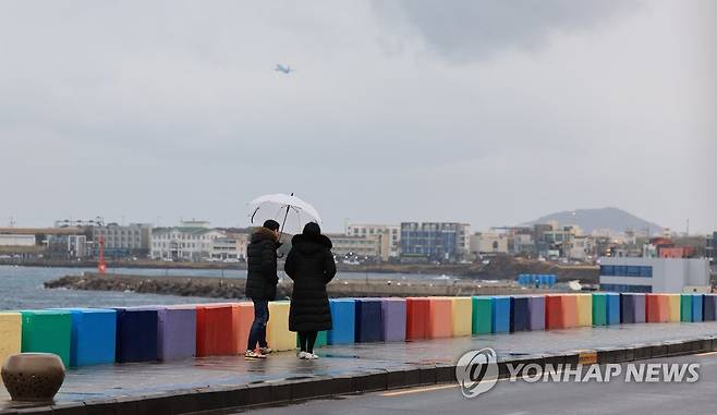 제주시 용담해안도로를 찾은 관광객들이 우산을 들고 바다 정취를 즐기고 있다. [연합뉴스 자료사진]