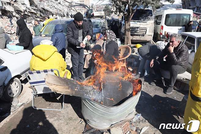 7일(현지시간) 튀르키예 카흐라만마라슈에서 구조대원과 사람들이 모닥불 옆에서 몸을 녹이고 있다. 설상가상으로 내린 눈이 잔해 위에 쌓여 구조작업을 더 어렵게 만들고 있다. ⓒ AFP=뉴스1 ⓒ News1 권진영 기자