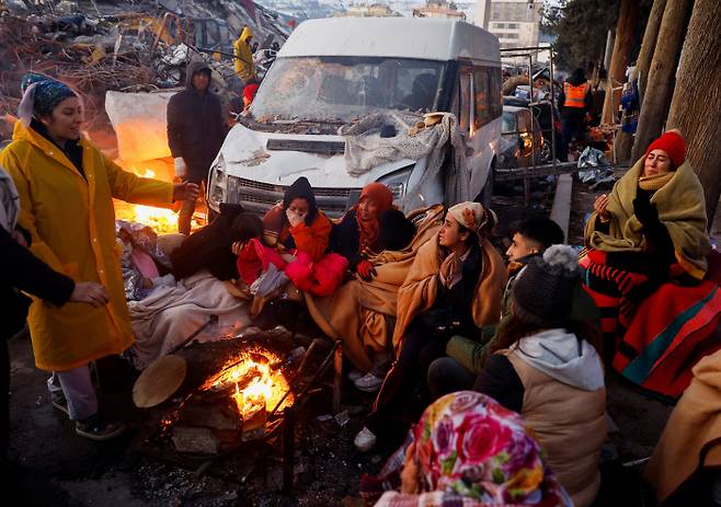 튀르키예 강진 속에서 살아남은 카흐라만마라스 주민들이 8일(현지시간) 건물 잔해들이 널브러진 거리에서 추위를 견디기 위해 피워놓은 모닥불 주위에 모여 있다. 로이터연합뉴스