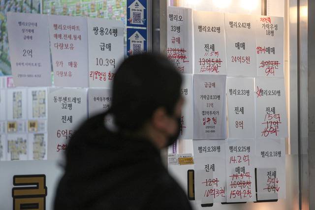 시민이 8일 서울 시내 한 공인중개소 앞을 지나가고 있다. 사무소 벽에는 손글씨로 가격이 수정된 아파트 매매 및 전세 매물 광고가 붙어있다. 고금리 영향으로 매매 수요가 줄면서 지난해 주택 매매 중 아파트 비중은 역대 최저를 기록했다. 연합뉴스