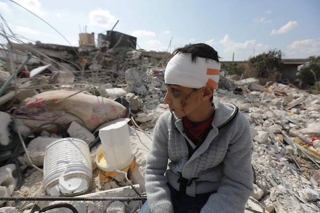11일(현지시간) 시리아 알레포주 진데리스에서 한 소년이 머리에 붕대를 감은 채 지진으로 붕괴한 건물 잔해 더미에 앉아 있다. 이 소년은 시리아와 인접한 튀르키예 남동부에서 지난 6일 발생한 강진으로 가족을 잃었다. 이번 지진으로 지금까지 양국에서 3만명 이상이 사망했다. [연합]