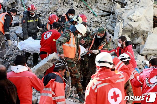 지난 9일 (현지시간) 규모 7.8의 강진이 강타한 시리아 자블레의 붕괴된 건물 잔해 아래에서 레바논 구조대원이 희생자를 들 것에 싣고 있다. ⓒ AFP=뉴스1 ⓒ News1 우동명 기자
