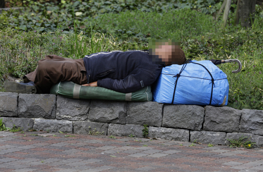 일본의 한 공원에서 노숙자로 보이는 노인이 잠을 자고 있다. AP 뉴시스