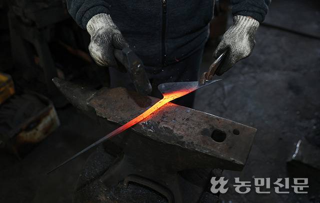 석노기 장인이 모루 위에 빨갛게 달군 쇠를 올려두고 망치로 두드리고 있다.