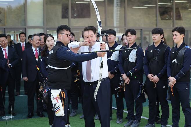 양궁 국가대표 김우진(좌)의 도움을 받아 활시위를 당겨보는 윤석열 대통령, 연합뉴스