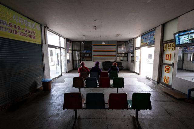 털모자를 쓴 지역 주민들이 14일 전북 김제시 원평공용버스터미널에서 버스를 기다리고 있다. 굳게 닫힌 매표소 셔터와 전등 하나 켜지지 않은 터미널의 황폐한 모습은 소멸하는 지방의 모습과 일맥상통한다. 지역이 쇠퇴해 교통도 쇠퇴하고, 교통이 쇠퇴해 지역이 쇠퇴하는 악순환인 것이다.