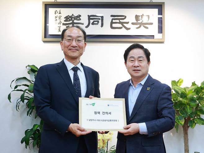 주광덕 시장(오른쪽)이 이성해 위원장에서 정책건의서를 전달하고 기념촬영을 하고 있다.(사진=남양주시 제공)