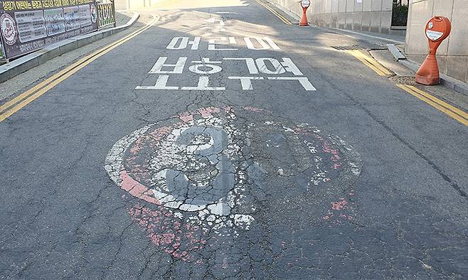 지난 21일 서울 마포구 서교초등학교 인근 폭 7m 도로에 새겨진 어린이 보호구역 속도제한 표시. 거의 지워져 애초 ‘(30)’이었을 숫자 형태를 알아보기 어렵다. 김동환 기자
