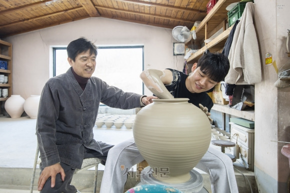 경북 문경의 ‘문경 망댕이 사기요’ 주인 김영식(왼쪽)씨가 백자 달항아리를 빚는 아들 김동연씨를 보며 흐뭇하게 웃고 있다. 도예 가문의 명맥을 잇는 부자가 원형 그대로 보존하고 있는 망댕이 사기요는 지난 1월 국가민속문화재로 지정 예고됐다.