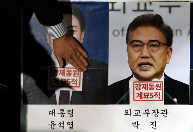 정의기억연대와 민족문제연구소 등 시민사회단체로 구성된 한일역사정의평화행동 관계자들이 6일 오후 서울광장에서 한국 정부가 발표한 강제동원 피해배상 해법을 규탄하는 촛불집회를 열고, 윤석열 대통령과 박진 외교부 장관의 사진에 '강제동원 계묘5적' 스티커를 붙이고 있다. 뉴스1