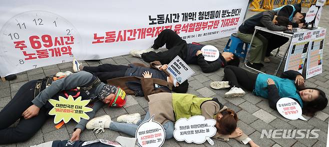 [서울=뉴시스] 민주노총이 지난 9일 서울 용산구 대통령집무실 앞에서 주당 최대 69시간 노동이 가능하도록 하는 근로시간 개편안에 반발하는 시위를 벌이고 있다. 이들은 "5일 연속 오전 9시부터 자정까지 일을 시키는 것을 합법화하는 개악안"이라며 과로사 퍼포먼스를 하고 있다.