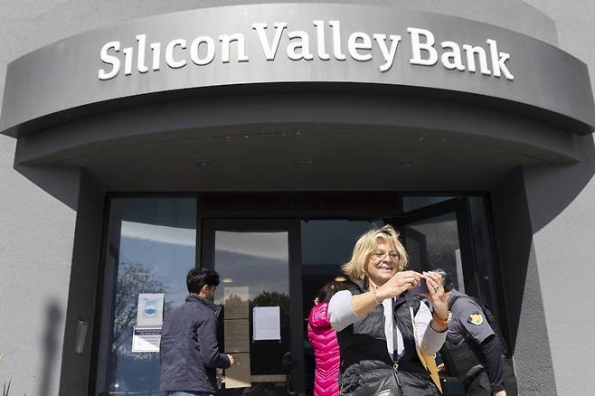 [샌타클래라=AP/뉴시스] 13일(현지시간) 미 캘리포니아주 샌타클래라 실리콘밸리은행(SVB) 본점 앞에서 대기하다가 입장하게 된 여성이 셀카를 찍고 있다. 예금주들은 돈을 찾기 위해 은행 밖에서 줄을 서서 대기했으며 연방정부는 SVB 예금주들이 인출할 수 있는 자금을 확보하기 위해 SVB에 개입한 것으로 알려졌다. 2023.03.14.
