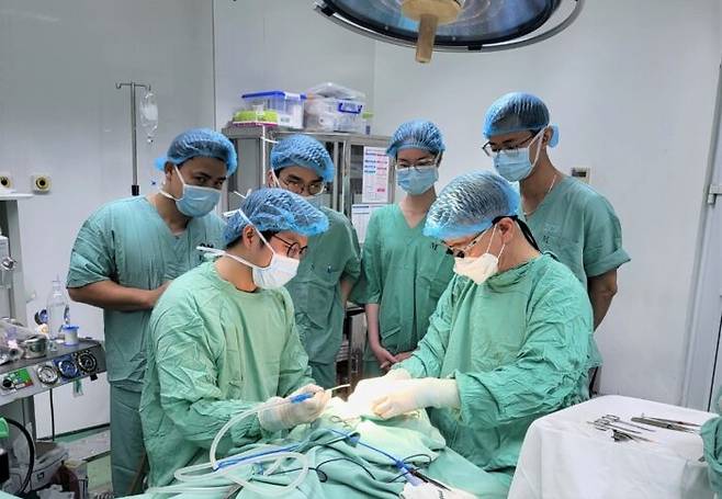 '인지클럽' 배용찬 교수(앞줄 오른쪽)가 베트남에서 구순구개열 어린이 환자를 수술하면서 현지 의료진에 수술법을 가르치고 있다. [사진=부산대병원]