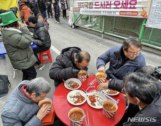 [대구=뉴시스] 정재익 기자 = 지난달 2일 오후 대구 북구 이슬람사원 공사현장 앞에서 대현동 주민들이 돼지수육과 소고기국밥을 먹고 있다. 2023.02.02. jjikk@newsis.com