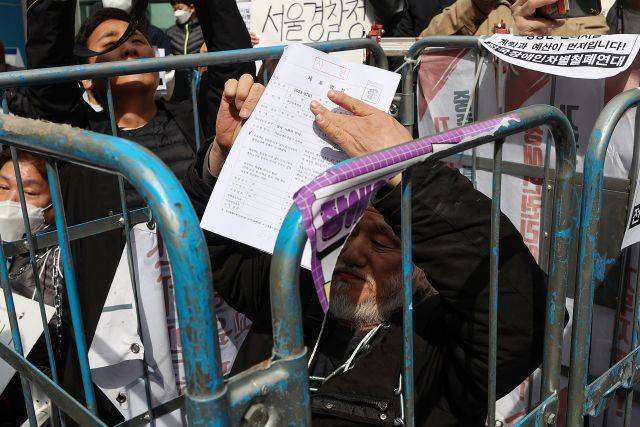 박경석 전국장애인차별철폐연대(전장연) 상임공동대표가 17일 오전 서울 종로구 서울경찰청 앞에서 자신의 체포영장을 들어 보이고 있다. 연합뉴스