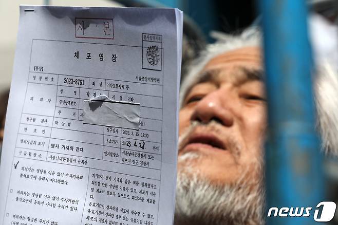 박경석 전국장애인차별철폐연대(전장연) 대표가 17일 오전 서울 종로구 서울지방경찰청 앞에서 법원의 체포영장 발부에 따른 입장발표 기자회견을 마치고 체포영장을 받아들고 있다. 2023.3.17/뉴스1 ⓒ News1 이승배 기자