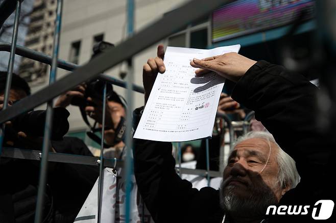박경석 전국장애인차별철폐연대(전장연) 대표가 17일 오전 서울 종로구 서울지방경찰청 앞에서 법원의 체포영장 발부에 따른 입장발표 기자회견을 마치고 경찰로부터 체포영장을 받아 들어보이고 있다.  2023.3.17/뉴스1 ⓒ News1 이승배 기자