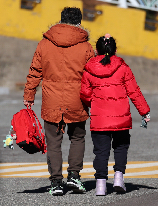 부산 남구 한 초등학교에서 한 학생이 한 손에는 아빠 손을 또 다른 손에는 핫팩을 쥐고 하교하고 있다. 연합뉴스