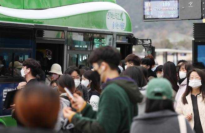 20일 월요일부터 버스와 전철 등 대중교통에서도 실내 마스크 착용 의무가 해제되고 자율로 전환된다. 그러나 당분간 마스크를 계속 쓰겠다는 사람들도 많다. 사진은 출근길 시민들이 버스를 기다리는 모습.