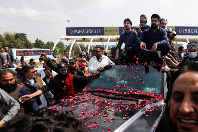 임란 칸 전 파키스탄 총리의 지지자들이 18일 수도 이슬라마바드 법정에 출석하는 그의 차량을 엄호하고 있다. 이슬라마바드=로이터 연합뉴스