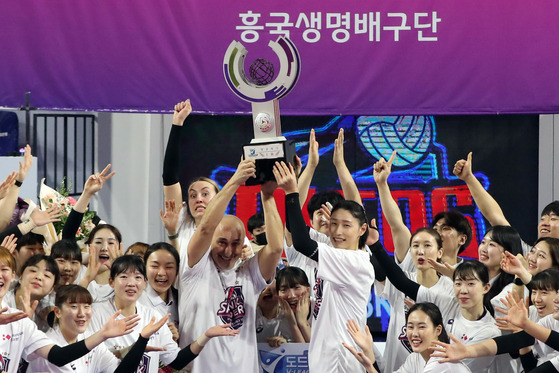 Kim Yeon-koung of the Incheon Heungkuk Life Pink Spiders, center right, lifts the V League trophy with head coach Marcello Abbondanza after securing the title following a 3-0 victory over the Hwaseong IBK Altos on Wednesday at Hwaseong Gymnasium in Hwaseong, Gyeonggi. [NEWS1]