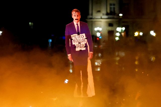 프랑스 정부의 연금개혁에 반대하는 한 시위자가 17일(현지시간) 파리 콩코르드 광장에서 에마뉘엘 마크롱 대통령을 묘사한 팻말 옆에 불을 들고 서 있다. 로이터연합뉴스
