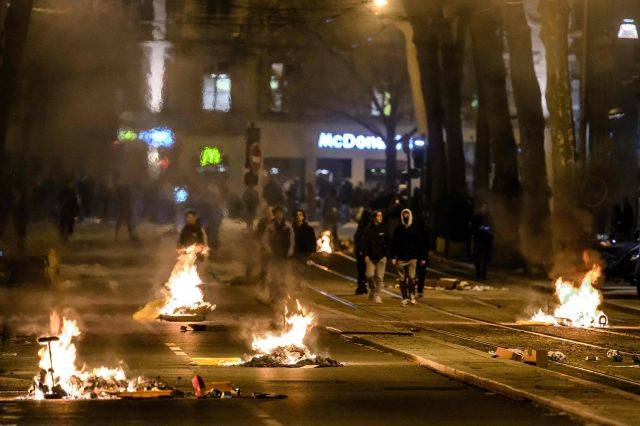 프랑스 에마뉘엘 마크롱 정부가 헌법49조3항을 근거로 의회 표결 없이 연금개혁 법안을 통과시킨 가운데 동부 리옹 시민들이 20일(현지시간)  불타는 쓰레기가 널려 있는 거리를 지나가고 있다. AFP연합뉴스