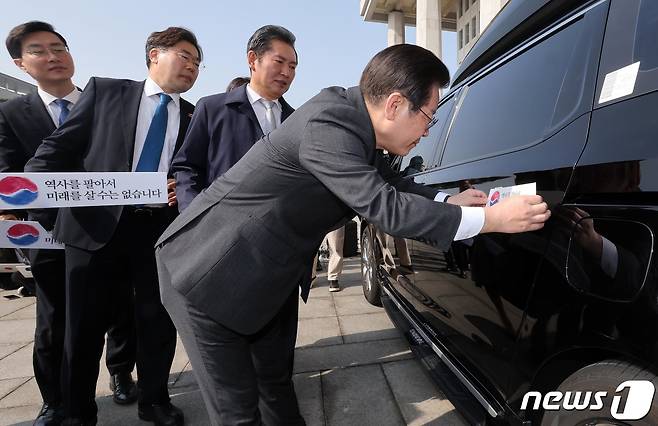이재명 더불어민주당 대표가 22일 서울 여의도 국회에서 대일굴종외교 규탄 태극기달기 운동 행사의 일환으로 차량에 태극마크와 '역사를 팔아서 미래를 살 수는 없습니다'라고 적힌 스티커를 부착하고 있다. (공동취재) 2023.3.22/뉴스1 ⓒ News1 안은나 기자