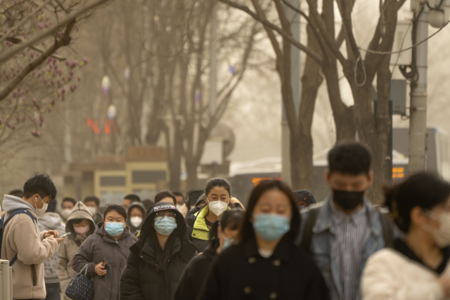황사로 뒤덮인 베이징의 중심상업지구에서 22일 마스크를 쓴 사람들이 거리를 걷고 있다. AP연합