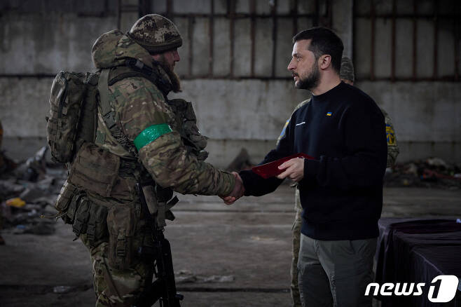 22일(현지시간) 볼로디미르 젤렌스키 우크라이나 대통령이 동부 격전지 바흐무트에 방문한 가운데 한 병사와 악수를 하고 있다. 이날 젤렌스키 대통령은 병사들을 "영웅＂이라 칭하며 훈장을 수여했다. ⓒ 로이터=뉴스1 ⓒ News1 박재하 기자