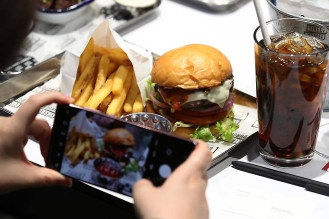 27일 오후 서울 강남구 현대백화점 무역센터점에 개점을 하루 앞둔 고든램지 스트리트 버거 매장에서 열린 미디어행사에서 참석자가 버거 사진을 찍고 있다.ⓒ뉴시스