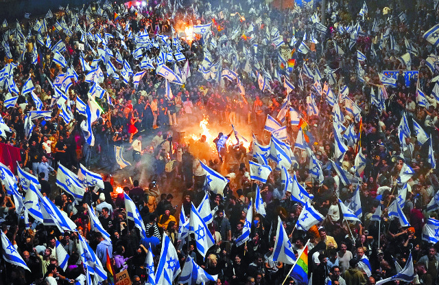 베냐민 네타냐후 이스라엘 총리가 이끄는 극우 연정의 사법 개혁에 반대하는 시민들이 26일(현지시간) 텔아비브의 한 고속도로에서 국기를 흔들며 시위를 벌이고 있다. 이날 이스라엘 총리실이 사법 개혁을 공개 비판한 요아브 갈란트 국방장관을 해임한다고 발표하자 시위는 더 격렬해졌다. AP연합뉴스