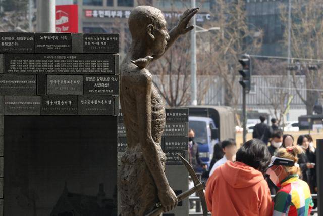 일본 초등학생이 내년도부터 사용할 사회 교과서에서 일제강점기 조선인 징병에 관한 기술이 강제성을 희석하는 방향으로 변경 발표된 28일 서울 용산구 용산역광장에 자리한 강제징용노동자상 앞으로 시민이 지나고 있다. 뉴스1