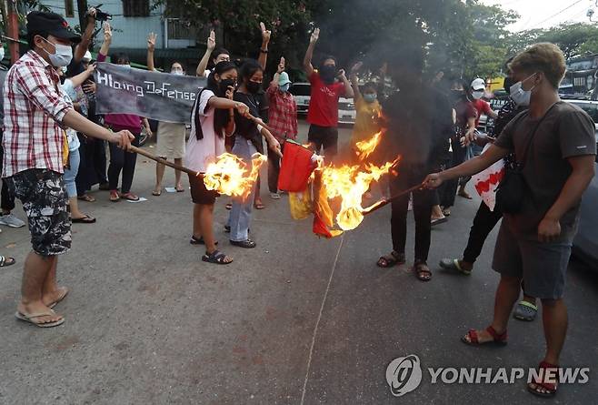 국기 불태우는 미얀마 반정부 시위대 (양곤 EPA=연합뉴스) 미얀마 최대 도시 양곤에서 2021년 군부 쿠데타 항의 시위대가 국기를 불태우며 저항의 표시로 세 손가락 경례를 하고 있는 모습.jsmoon@yna.co.kr