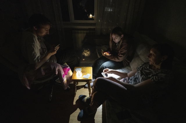 수도 키이우는 매일 단전, 단수가 반복된다. 키이우의 나탈리 가족이 충전식 LED 등과 핸드폰 라이트를 켜고 카드게임을 하고 있다. 남편은 전쟁에 나갔다(키이우, 2023년 2월). KISH KIM 사진